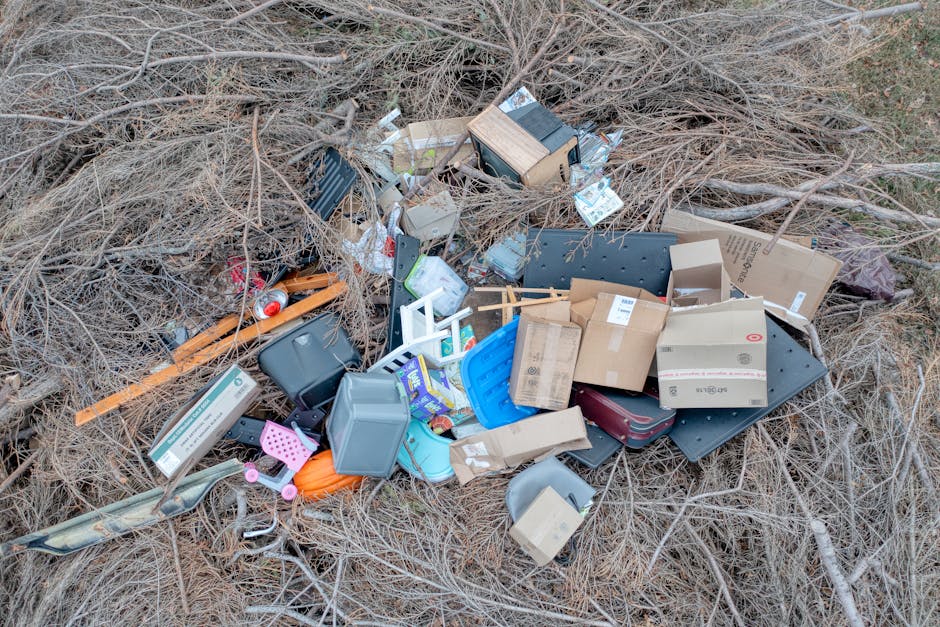 A ground area featuring scattered cardboard boxes, many of which are crushed or torn, with some displaying a green and white star logo, along with other miscellaneous paper and plastic waste. The boxe